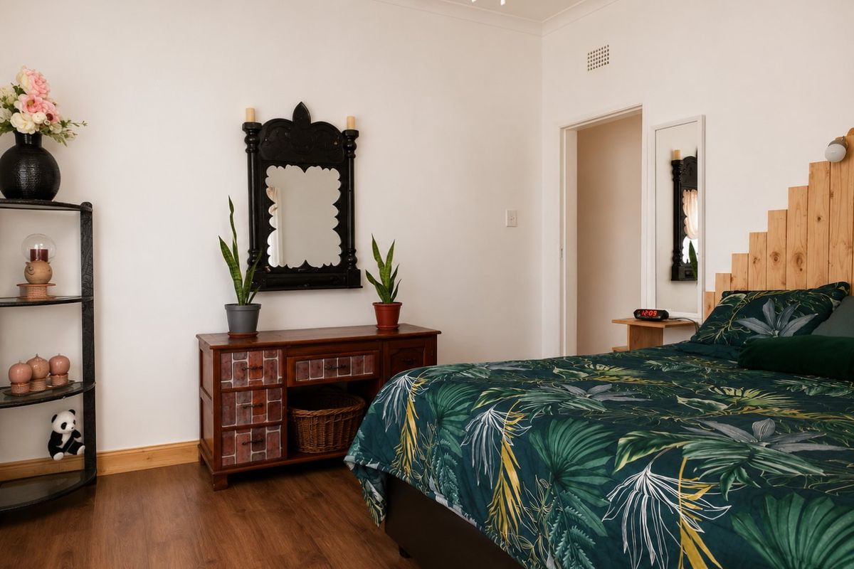 A well-maintained bedroom featuring laminate flooring, neutral walls, and a decorative wooden headboard, offering a comfortable and functional living space.