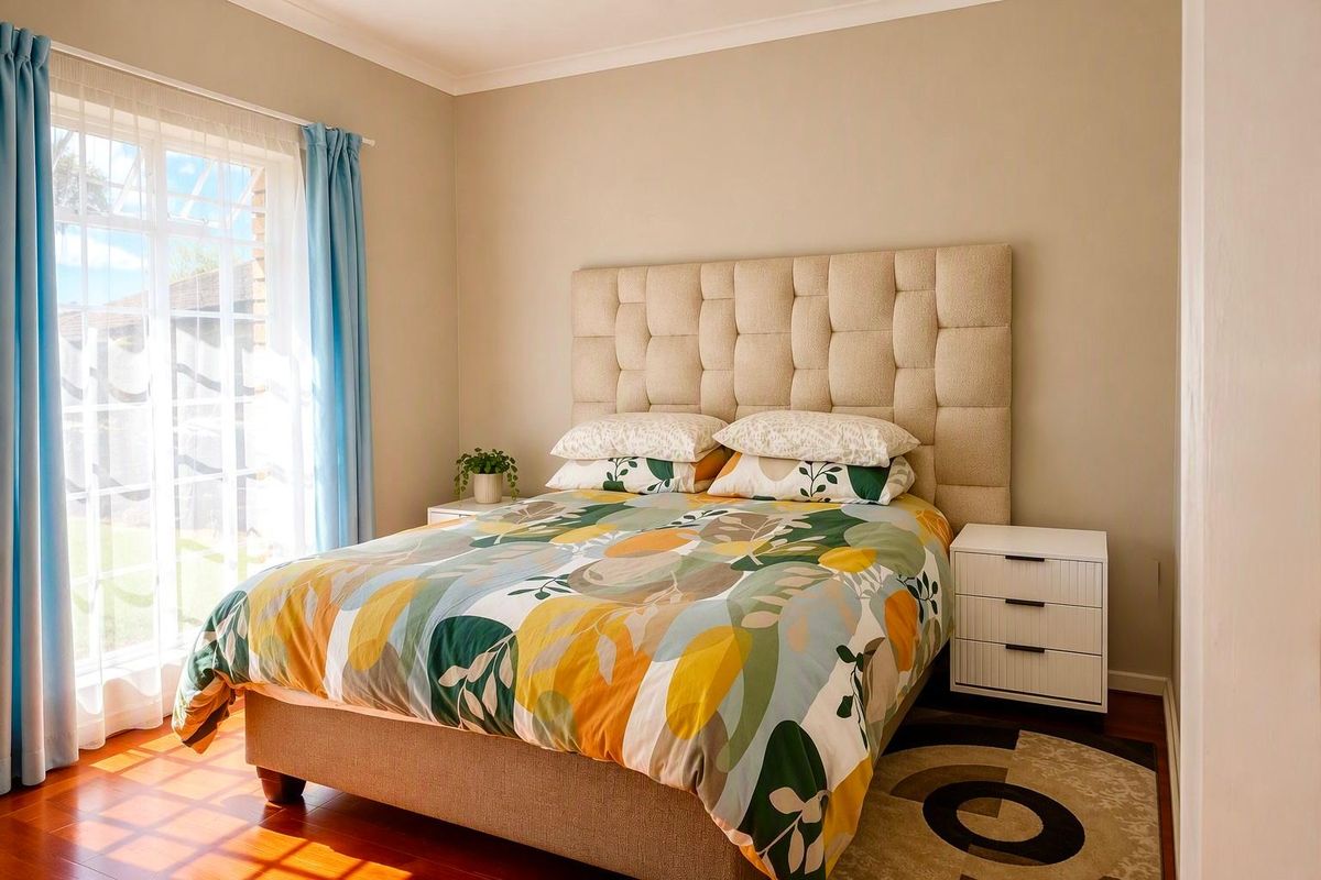 A well-maintained bedroom featuring warm timber flooring, neutral wall tones, and a large sliding glass door providing natural light and garden access.