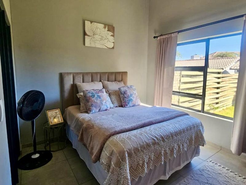 A well-lit bedroom featuring tiled flooring and a large window that allows for natural light, creating a comfortable living space.