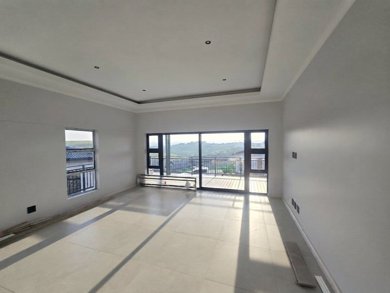 Spacious, light-filled living area featuring modern tiled floors, recessed ceiling detail, and large sliding doors opening to an outdoor balcony with scenic views.