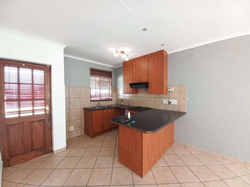 A functional kitchen featuring laminate cabinetry, dark countertops, ceramic tile flooring, and a built-in hob with an extractor fan.
