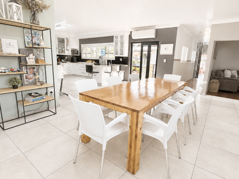 Spacious open-plan dining and kitchen area featuring modern tiled flooring, neutral walls, and direct access to the outdoor space via sliding glass doors.