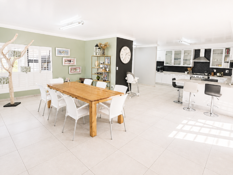 Spacious open-plan living area featuring a modern kitchen with island seating, tiled floors, and a dedicated dining space with natural light.