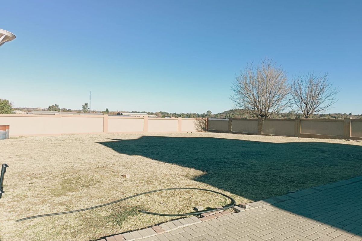 A spacious, level residential backyard featuring a well-maintained perimeter wall and a paved patio area, offering a clean canvas for landscaping.