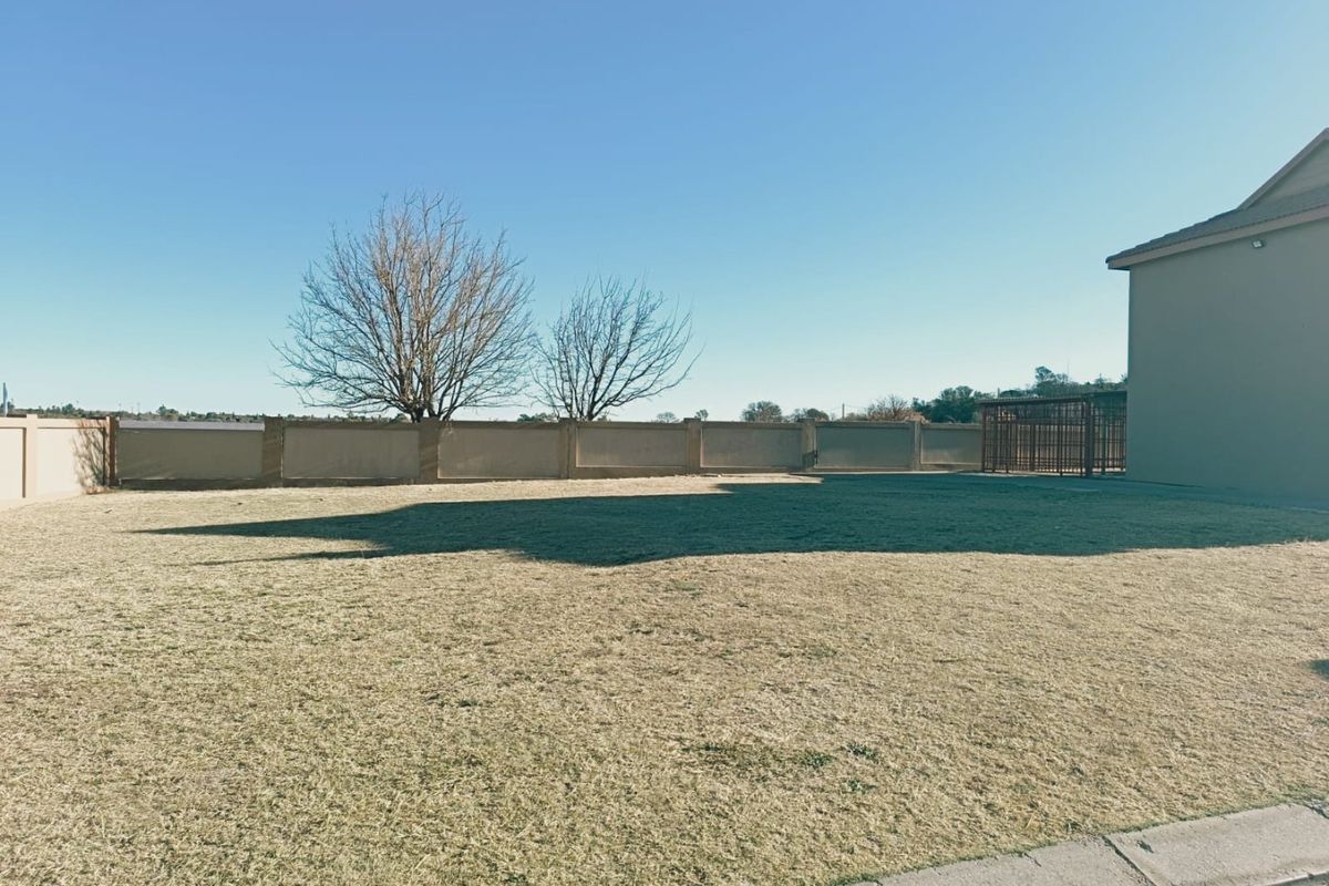 A spacious, level residential plot featuring a well-defined perimeter wall and established grass lawn, offering a clear area for potential development.