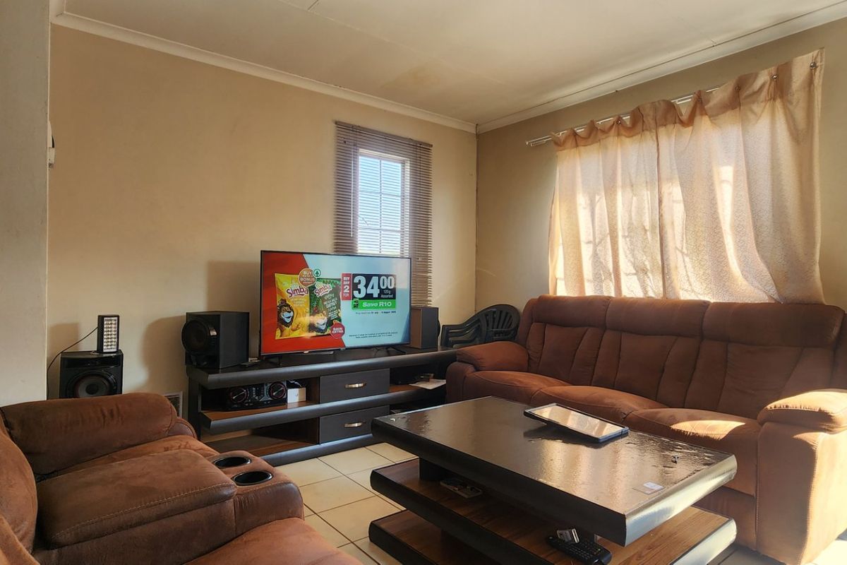 A living room featuring tiled flooring, cove cornicing, and natural light through window blinds, offering a functional space ready for cosmetic updates.