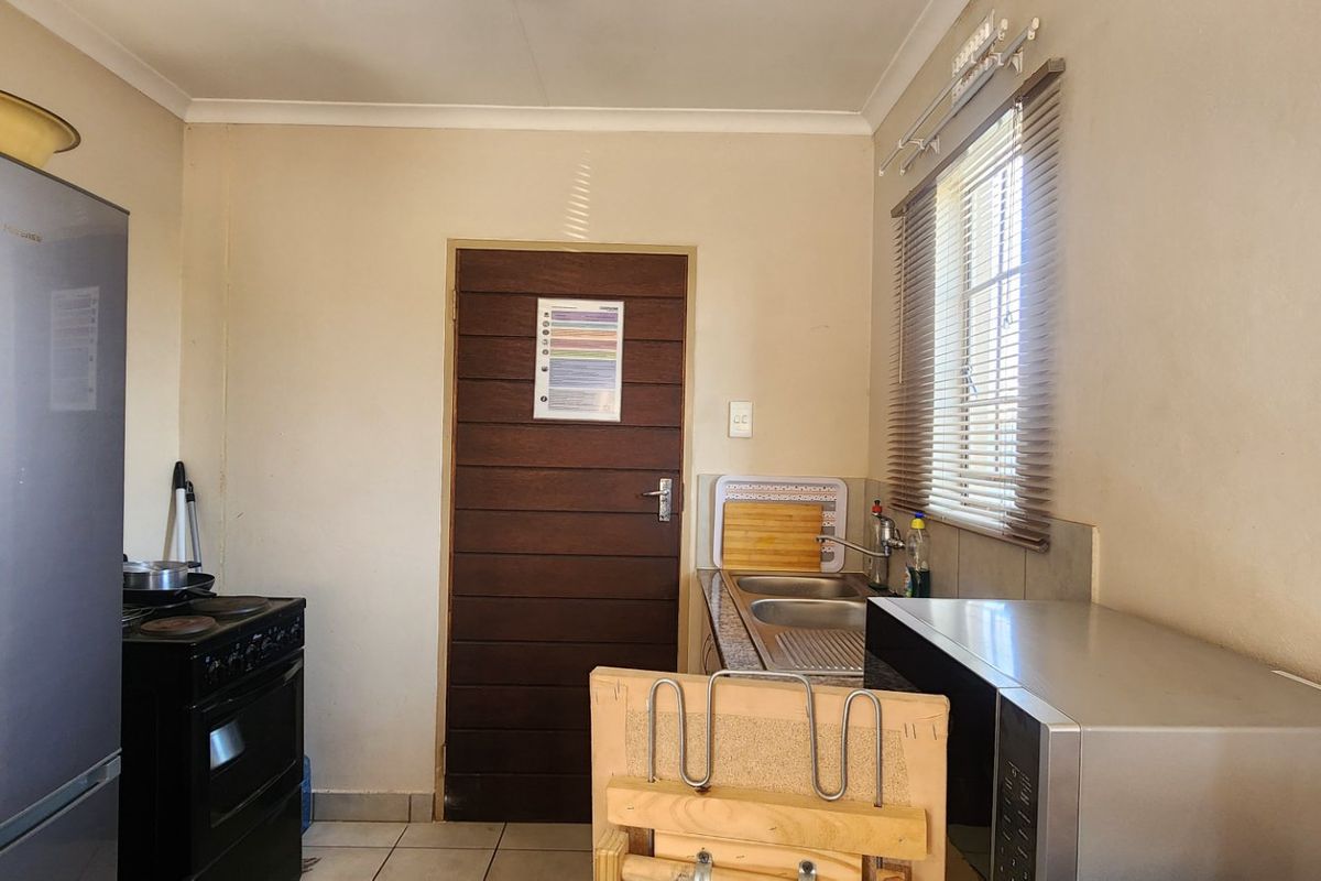A functional kitchen featuring tiled flooring, a stainless steel sink, and a window with fitted blinds.