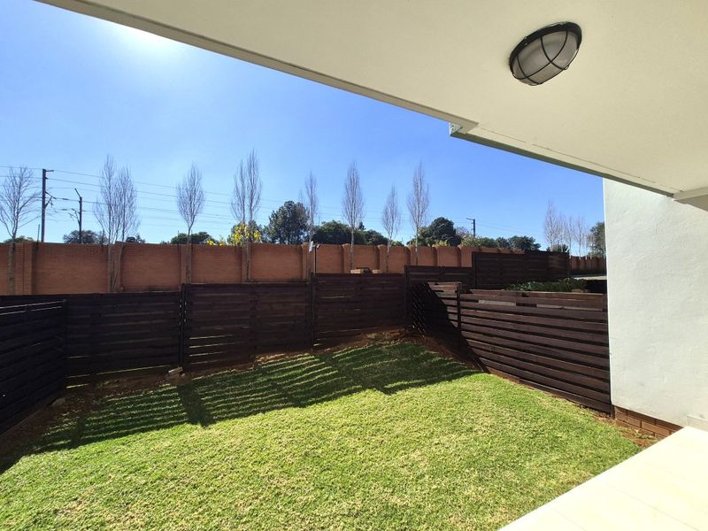 A covered patio area overlooking a private garden space enclosed by timber slat fencing and a brick perimeter wall.