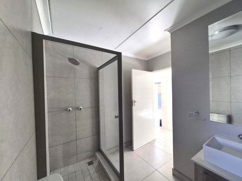 Modern bathroom featuring a walk-in shower with glass enclosure, tiled finishes, and a contemporary vanity basin.