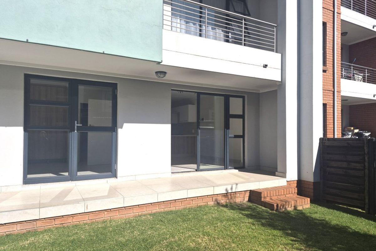Ground floor apartment patio featuring tiled flooring, brick steps, and direct access to a private garden area through sliding glass doors.