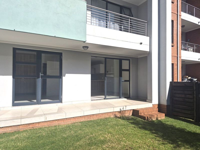 Ground floor apartment patio featuring tiled flooring, brick steps, and direct access to a private garden area through sliding glass doors.