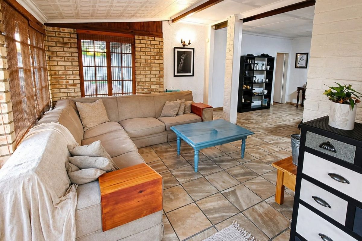Spacious living area featuring exposed brick walls, tiled flooring, and textured ceiling tiles, offering a rustic and functional living space.