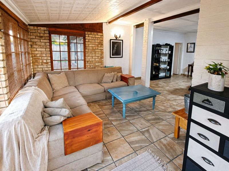 Spacious living area featuring exposed brick walls, tiled flooring, and textured ceiling tiles, offering a rustic and functional living space.