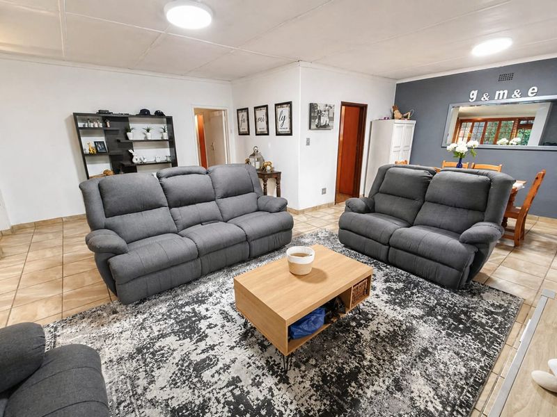 Spacious open-plan living and dining area featuring neutral tiled flooring and a contemporary accent wall, providing a versatile layout for family living.