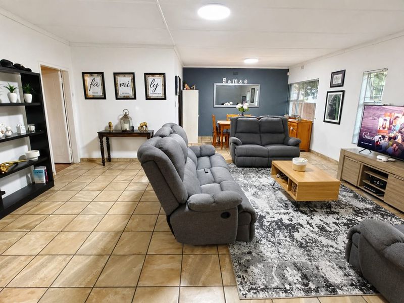 Spacious open-plan living and dining area featuring neutral ceramic tile flooring and a dark blue accent wall.