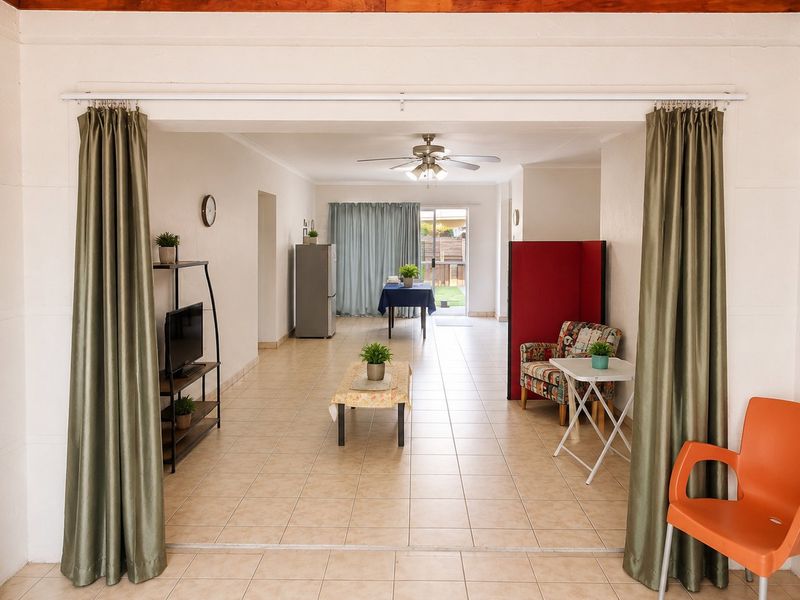 Spacious open-plan living area featuring tiled flooring, a ceiling fan, and direct access to the rear outdoor space through sliding glass doors.