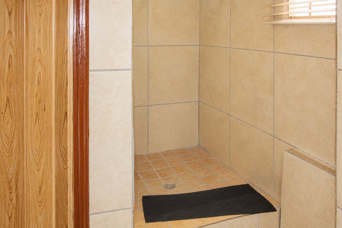 A functional bathroom shower area featuring neutral wall and floor tiling with a built-in shower base.