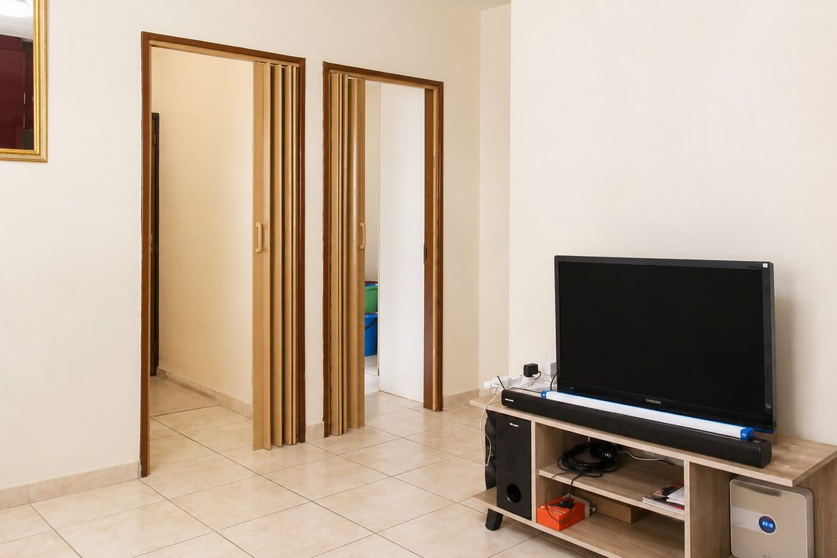 Living area featuring neutral ceramic floor tiles and dual folding doors providing access to adjacent rooms.