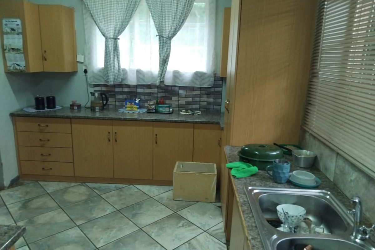 A functional kitchen featuring laminate cabinetry, stone-look countertops, a double stainless steel sink, and tiled flooring.
