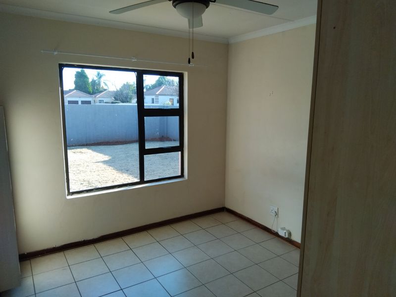 A vacant bedroom featuring tiled flooring, a ceiling fan, and a built-in cupboard, offering a blank canvas for personalization.