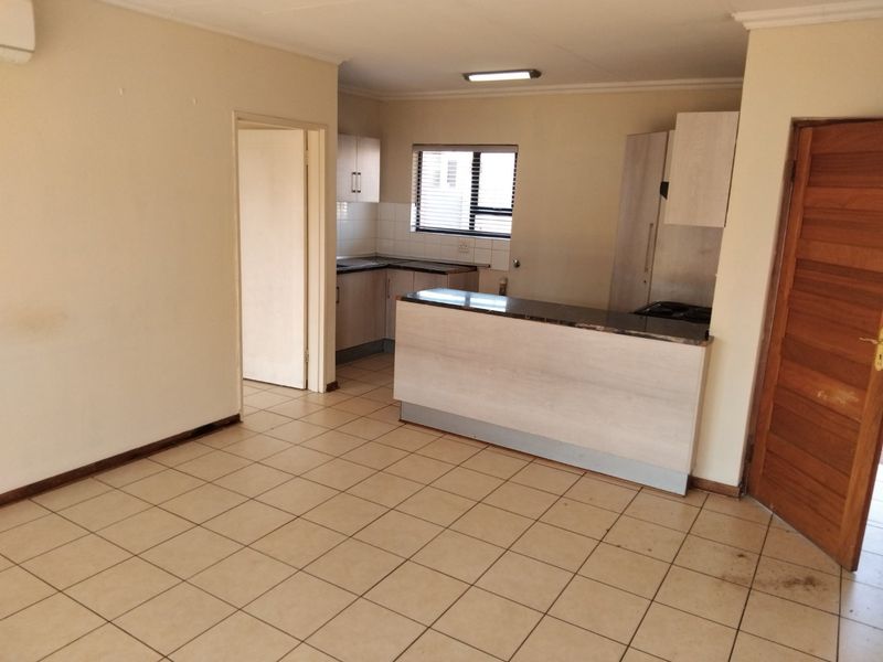 Open plan living and kitchen area featuring tiled flooring, built-in cabinetry, and a breakfast bar, offering a functional blank canvas for interior design.