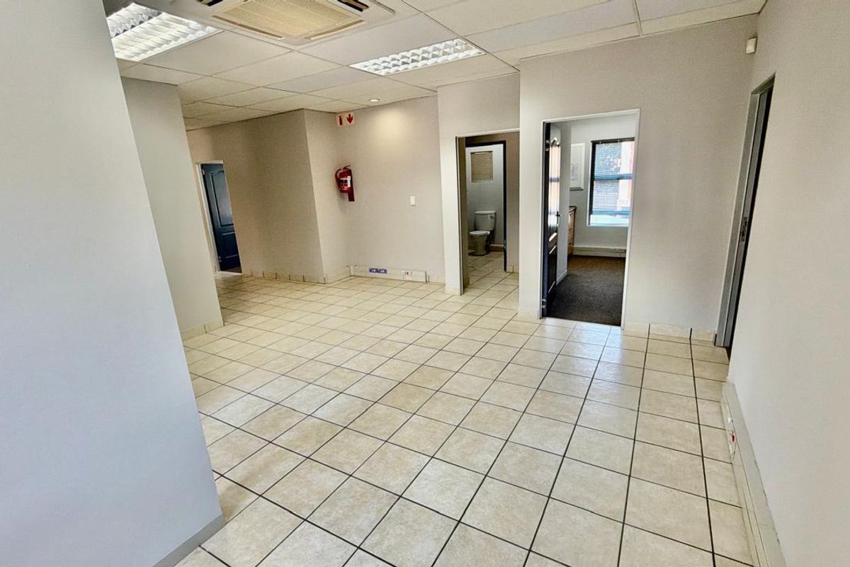 Open plan commercial office space featuring ceramic tiled flooring, suspended ceilings with recessed lighting, and access to multiple internal rooms.