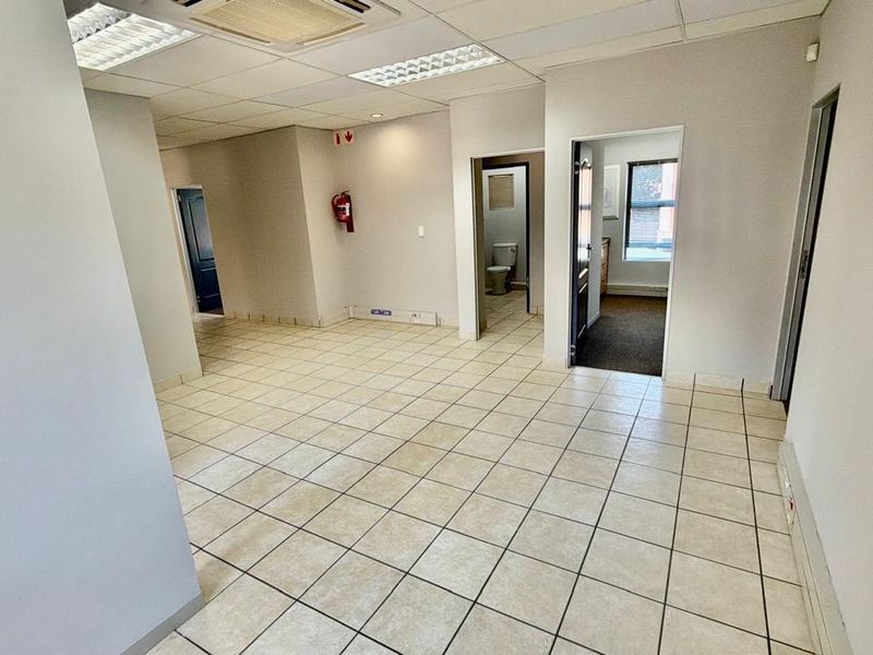 Open plan commercial office space featuring ceramic tiled flooring, suspended ceilings with recessed lighting, and access to multiple internal rooms.