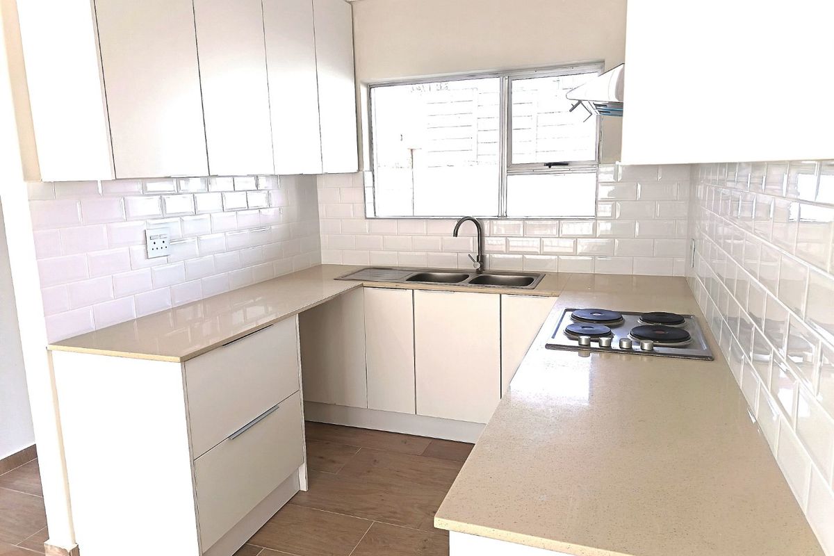 Modern kitchen featuring white cabinetry, subway tile backsplash, stone countertops, and a built-in electric hob with an extractor fan.