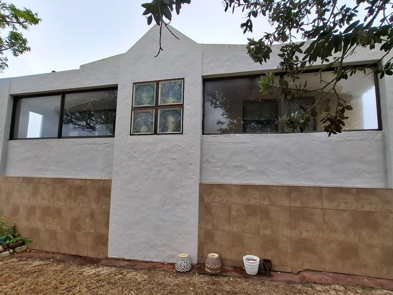 Front facade of the property featuring a combination of stucco and tiled finishes with large sliding windows and a central decorative glass feature.