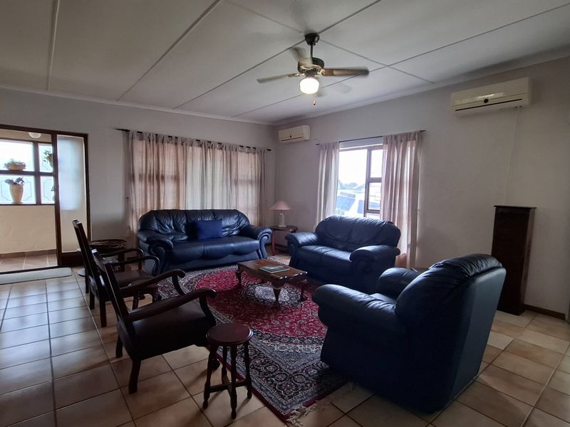 Spacious living room featuring tiled flooring, a ceiling fan, and a split-system air conditioner, providing a comfortable and functional living space.