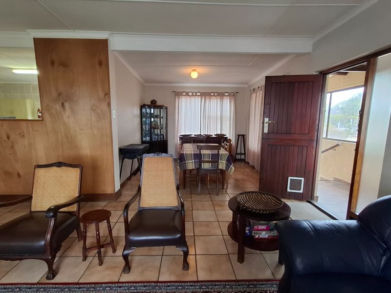 Open plan living and dining area featuring tiled flooring and timber wall paneling, with direct access to an outdoor patio space.