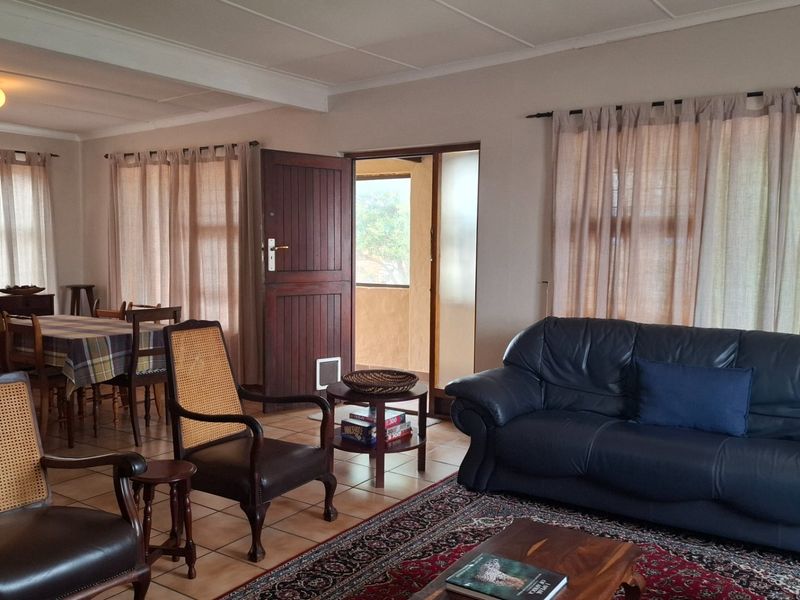 Spacious open-plan living and dining area featuring tiled flooring and direct access to an outdoor space through a timber door.