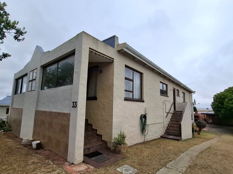 Exterior view of a single-story house featuring a stucco facade, tiled base detailing, and external staircase access.