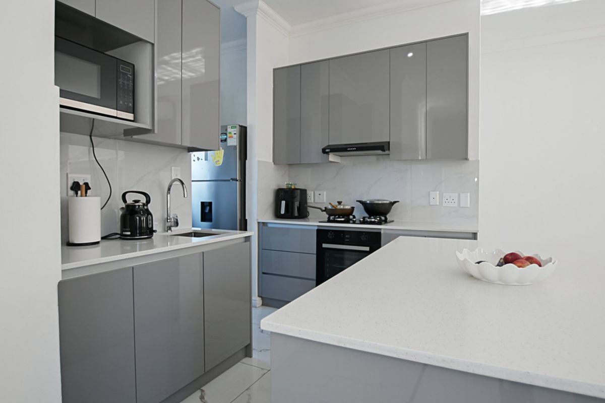 Modern kitchen featuring sleek grey cabinetry, white quartz countertops, integrated appliances, and high-quality finishes throughout.