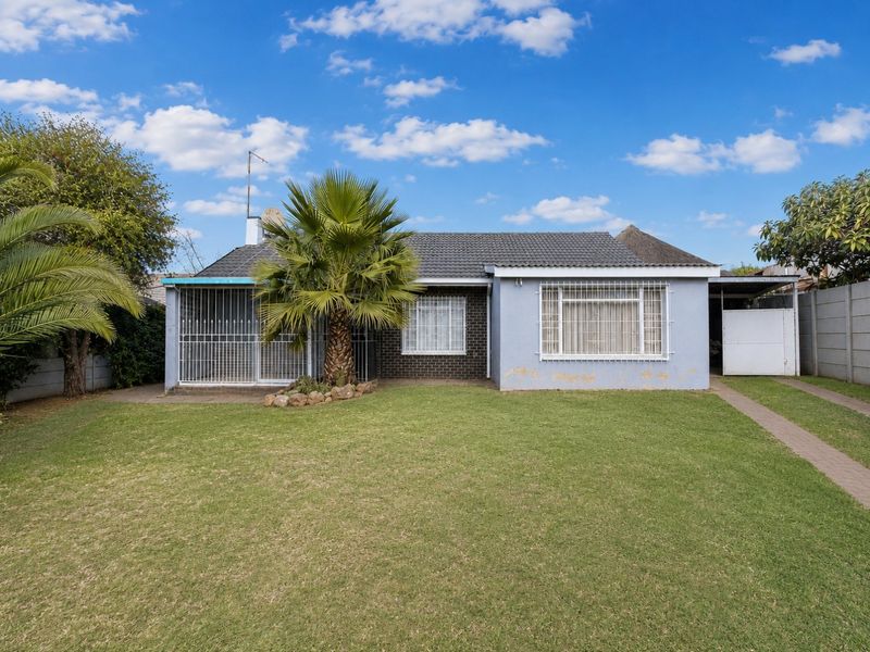 Front view of a single-story house featuring a tiled roof, security bars on windows, and a well-maintained front lawn with a paved driveway.