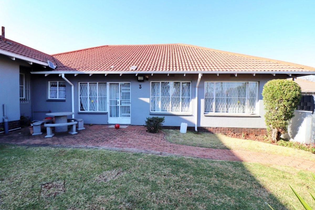 Rear view of the property featuring a tiled roof, brick paved patio area, and established garden space.
