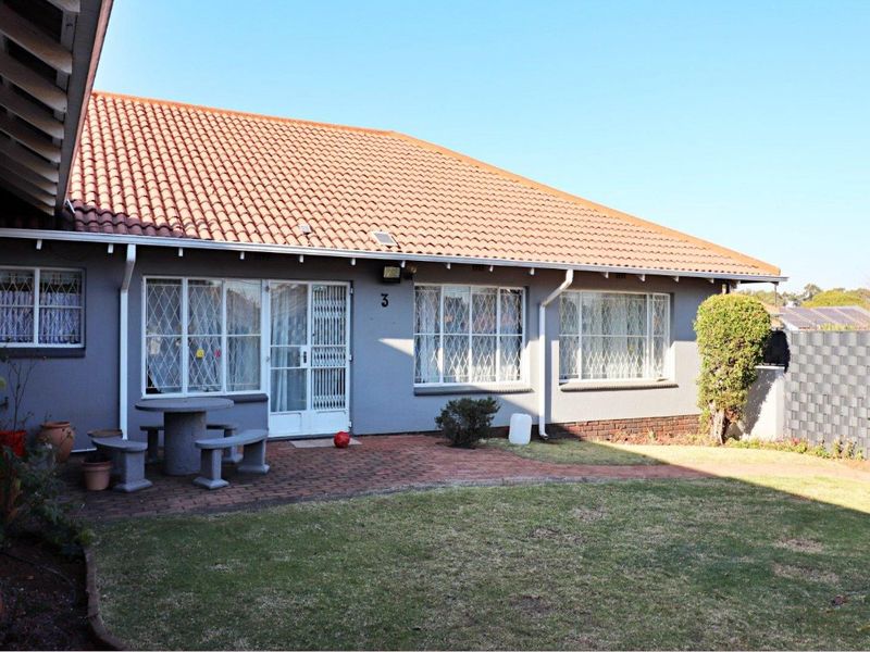 Rear view of the property featuring a tiled roof, brick paved patio area, and a well-maintained lawn.