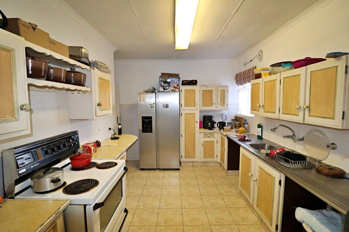 A functional kitchen featuring built-in cabinetry, an electric stove, and tiled flooring, offering a practical layout with potential for modern updates.