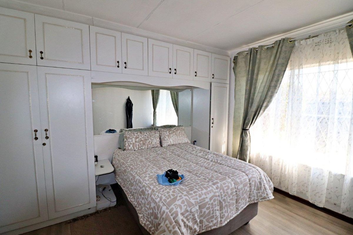 A bedroom featuring extensive built-in cabinetry with integrated mirrored headboard and light-toned laminate flooring.