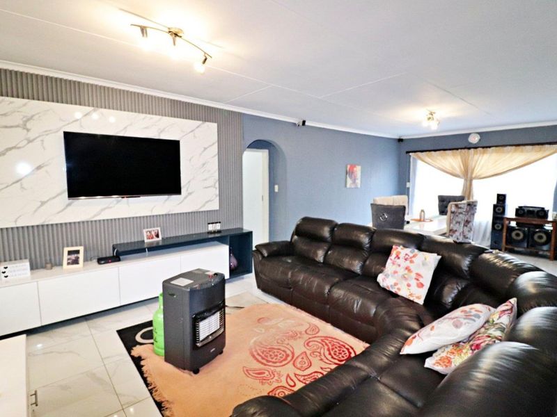 Spacious open-plan living and dining area featuring a modern marble-effect feature wall, built-in media cabinetry, and neutral tiled flooring throughout.