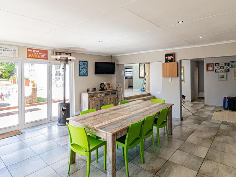 Spacious open-plan living and dining area featuring tiled flooring, recessed lighting, and large sliding glass doors providing direct access to the outdoor garden space.