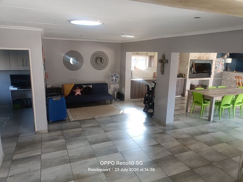 Spacious open-plan living and dining area featuring tiled floors, a built-in fireplace, and neutral wall finishes, offering a versatile layout for family living.