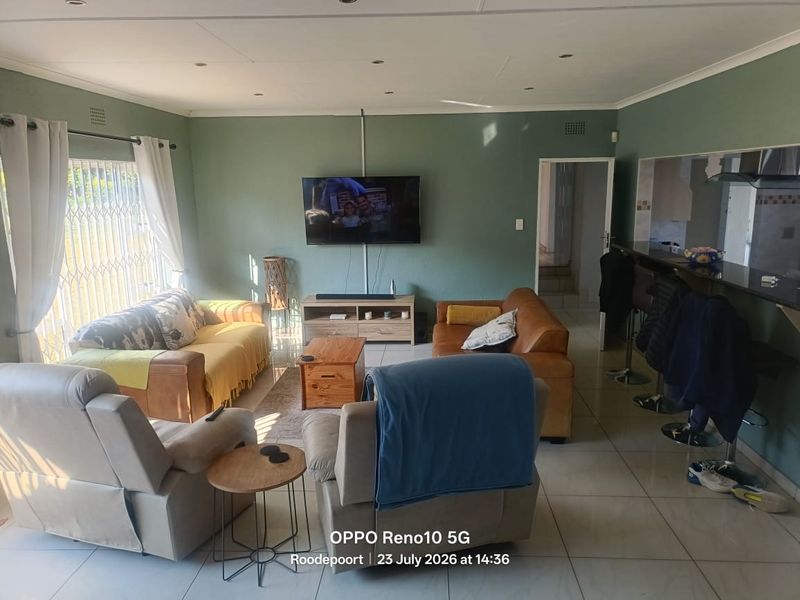 Open-plan living area featuring tiled floors, recessed lighting, and a breakfast bar connecting to the kitchen space.