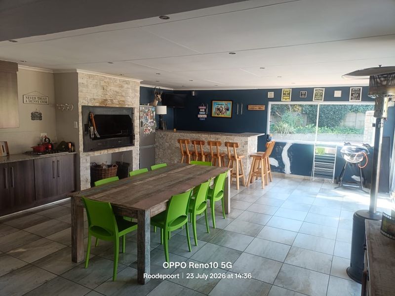 Spacious open-plan living and dining area featuring a built-in braai, stone-clad breakfast bar, and tiled flooring with direct access to the garden.