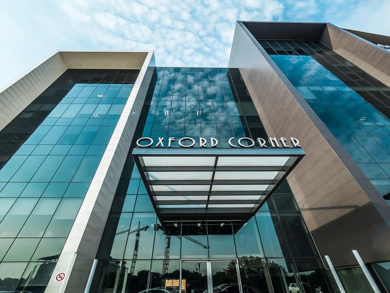 Modern commercial office building facade featuring a glass curtain wall, prominent signage, and a sleek entrance canopy.