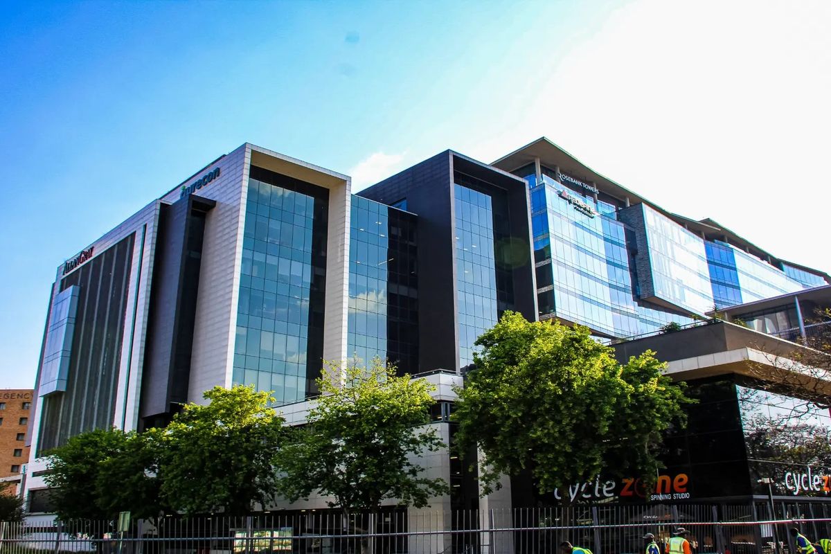 A modern multi-story commercial office building featuring extensive glass curtain walling, metal cladding, and prominent corporate signage.