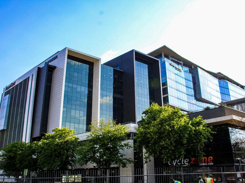 A modern multi-story commercial office building featuring extensive glass curtain walling, metal cladding, and prominent corporate signage.