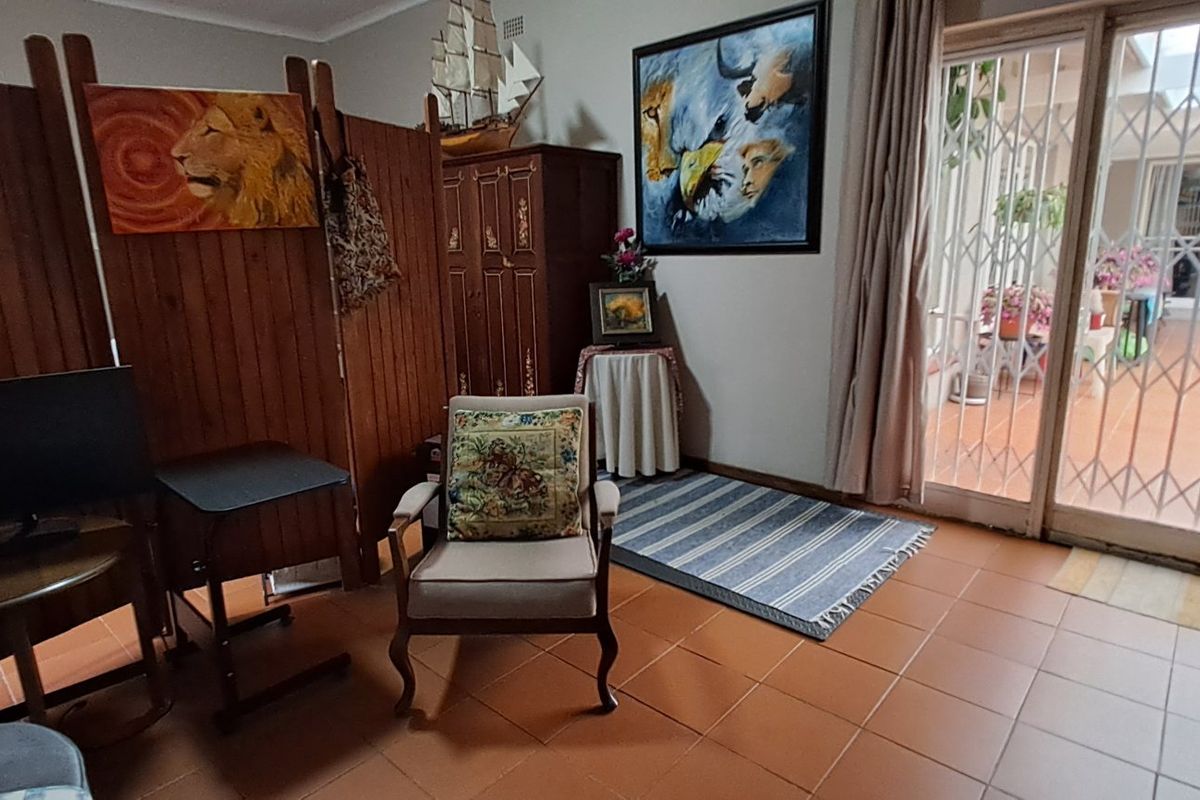 A living room featuring tiled flooring and a sliding glass door with a security gate leading to an outdoor patio area.