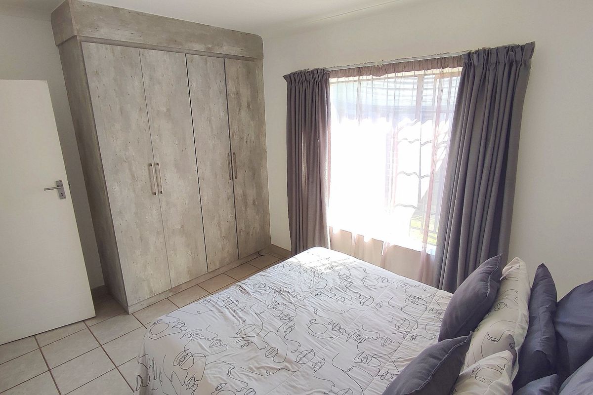 A well-maintained bedroom featuring neutral tiled flooring and a modern built-in wardrobe with a textured finish.