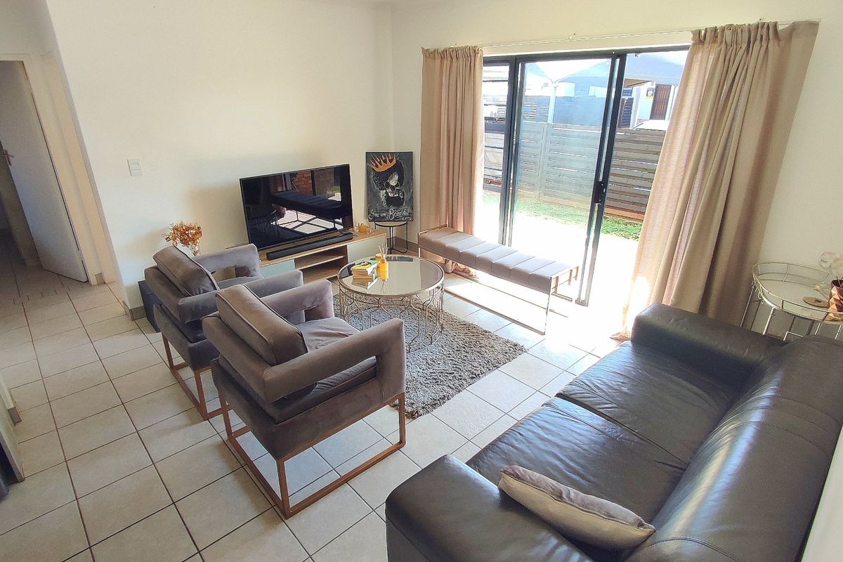 A bright living room featuring tiled flooring and a large sliding glass door providing access to the outdoor area.